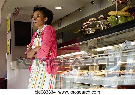 Picture - African American bakery owner standing in shop. Fotosearch