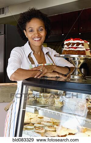 Stock Photo - African American bakery owner standing in shop. Fotosearch