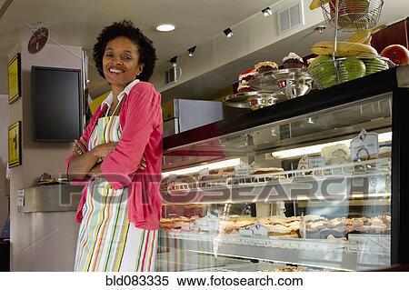 Stock Photography - African American bakery owner standing in shop. Fotosearch