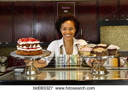 Stock Photo - African American bakery owner displaying baked goods. Fotosearch