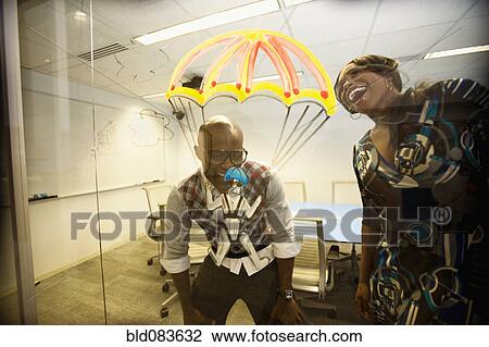 Stock Image - African American business people looking at golden parachute drawing. Fotosearch