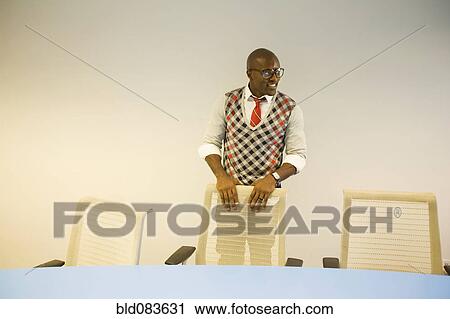 Stock Image - African American businessman standing in conference room. Fotosearch