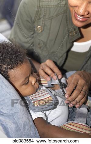 African American mother buckling baby into car seat View Large Photo Image Picture - African American mother buckling baby into car seat. Fotosearch