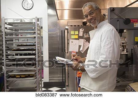 Stock Photo - African American small business owner working in bakery kitchen. Fotosearch