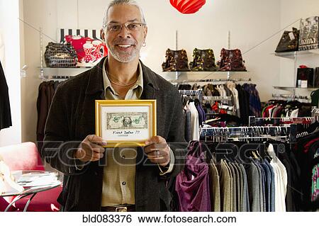 Stock Photograph - African American small business owner holding first dollar. Fotosearch