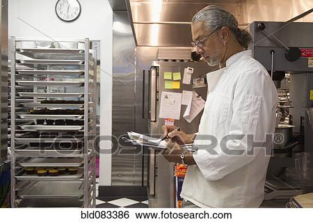 Stock Photograph - African American small business owner working in bakery kitchen. Fotosearch