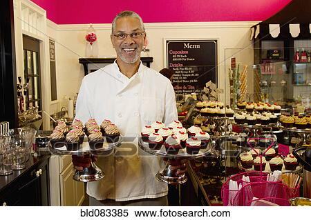 Stock Photography - African American small business owner with cupcakes in bakery shop. Fotosearch