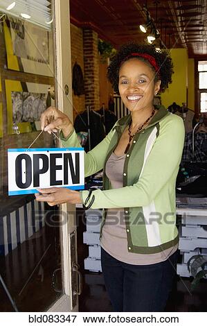 African American woman hanging open sign on door View Large Photo Image Stock Photo - African American woman hanging open sign on door. Fotosearch