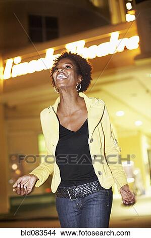 Picture - African American woman walking outdoors at night. Fotosearch