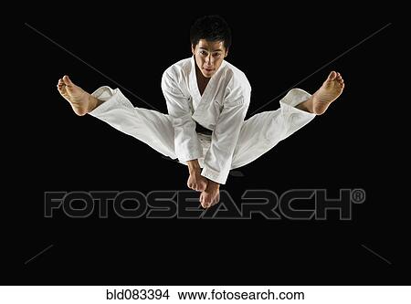 Picture - Asian male karate black belt kicking in air. Fotosearch