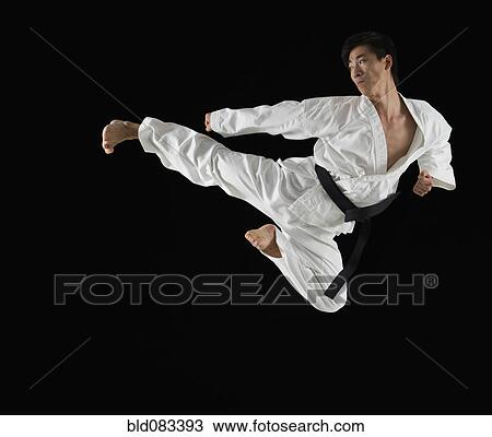 Stock Image - Asian male karate black belt kicking in air. Fotosearch
