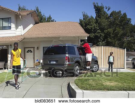 Stock Image - Black family washing car in driveway. Fotosearch
