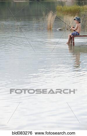 Stock Photograph - Caucasian boy fishing in lake. Fotosearch
