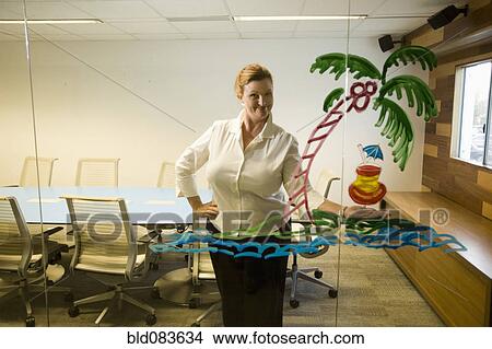 Picture - Caucasian businesswoman looking at drawing on conference room wall. Fotosearch