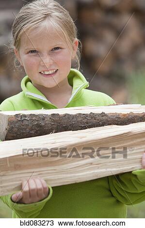 Stock Image - Caucasian girl carrying firewood. Fotosearch