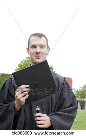 Caucasian graduate holding graduation cap View Large Photo Image Stock Photo - Caucasian graduate holding graduation cap. Fotosearch