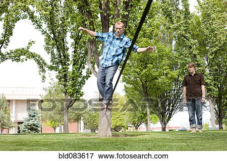 Caucasian man balancing on rope in park View Large Photo Image Stock Photo - Caucasian man balancing on rope in park. Fotosearch