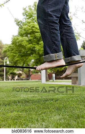 Stock Photograph - Caucasian man balancing on rope in park. Fotosearch