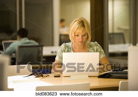 Stock Image - Caucasian woman using laptop in office. Fotosearch