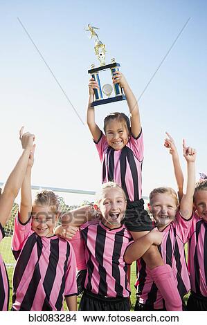 Picture - Cheering girl soccer players posing with trophy. Fotosearch