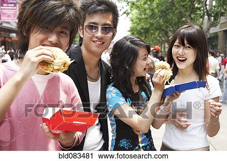 Stock Image - Chinese friends eating fast food together. Fotosearch