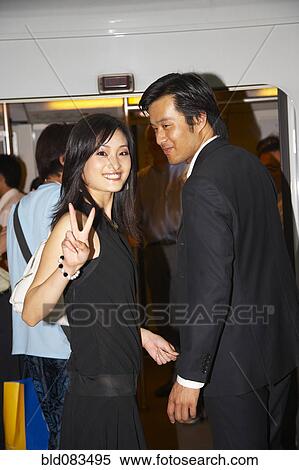Stock Photography - Chinese woman giving peace sign with boyfriend. Fotosearch