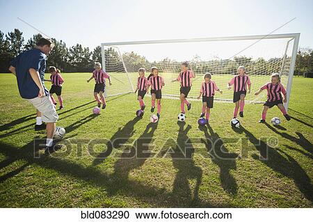 Stock Image - Coach practicing with girl soccer players. Fotosearch