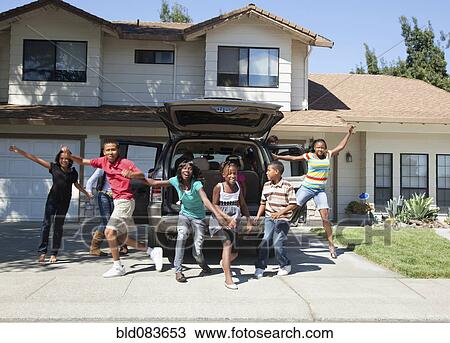 Stock Image - Family cheering in driveway of house. Fotosearch