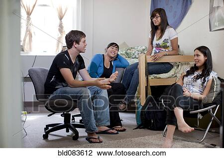 Stock Image - Friends hanging out in college bedroom together. Fotosearch
