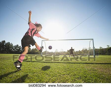 Picture - Girl soccer player kicking soccer ball at net. Fotosearch
