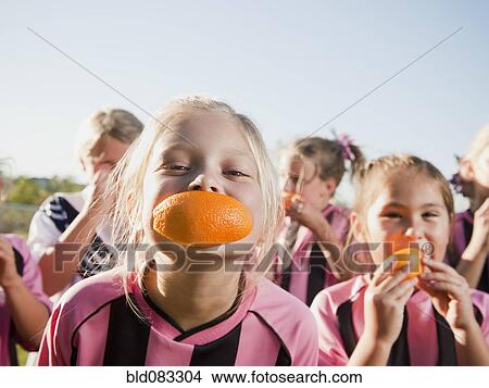 Picture - Girl soccer players eating orange slices. Fotosearch