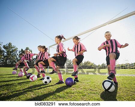 Stock Image - Girl soccer players practicing near net. Fotosearch