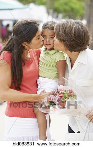 Stock Image - Grandmother and mother kissing child. Fotosearch