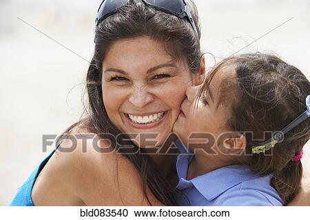 Stock Image - Hispanic daughter kissing smiling mother. Fotosearch
