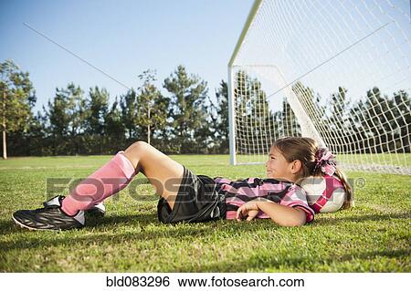 Stock Photograph - Hispanic girl soccer player laying with head on soccer ball. Fotosearch