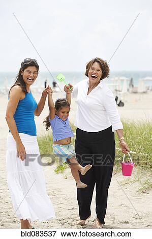 Stock Photo - Hispanic grandmother, mother and daughter enjoying beach. Fotosearch