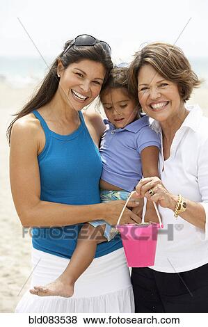 Stock Photo - Hispanic grandmother, mother and daughter enjoying beach. Fotosearch