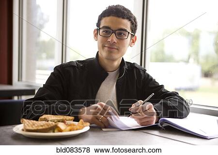 Hispanic student studying in diner and having lunch View Large Photo Image Stock Photo - Hispanic student studying in diner and having lunch. Fotosearch