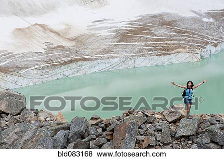 Stock Photo - Hispanic woman hiking hear glacial lake. Fotosearch