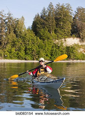 Picture - Hispanic woman kayaking on lake. Fotosearch