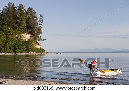 Stock Image - Hispanic woman kayaking on lake. Fotosearch
