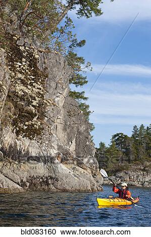 Stock Image - Hispanic woman kayaking on lake. Fotosearch
