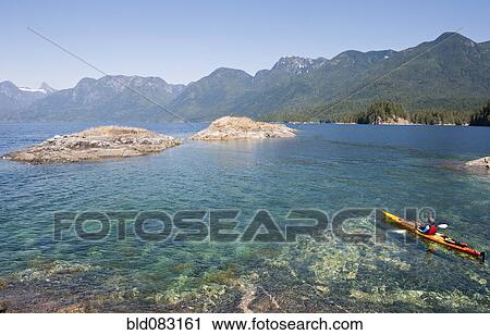 Stock Image - Hispanic woman kayaking on lake. Fotosearch