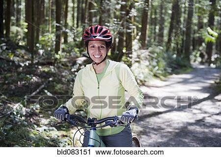 Stock Image - Hispanic woman riding mountain bike. Fotosearch