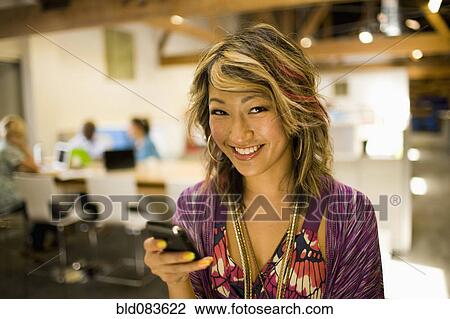 Japanese businesswoman using cell phone in communal workspace View Large Photo Image Stock Image - Japanese businesswoman using cell phone in communal workspace. Fotosearch