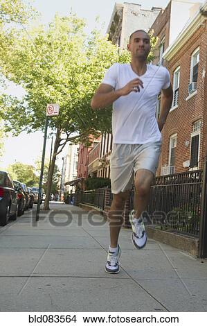 Picture - Mixed race man running on urban sidewalk. Fotosearch