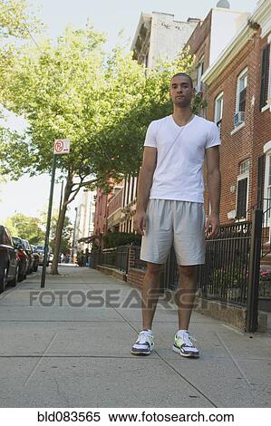 Stock Photography - Mixed race man standing on urban sidewalk. Fotosearch