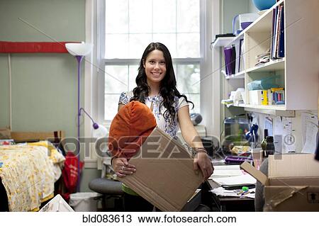 Stock Image - Mixed race woman moving into college dorm room. Fotosearch
