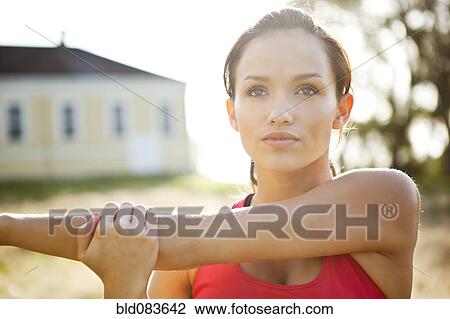 Stock Image - Mixed race woman warming up before exercise. Fotosearch