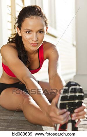 Stock Photo - Mixed race woman warming up before exercise. Fotosearch